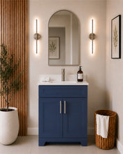 Pearl 24" navy blue bathroom vanity with brushed nickel hardware and white quartz countertop, styled in a modern bathroom with wood slat accent wall