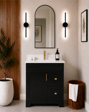 Pearl 30" black bathroom vanity with two drawers, gold hardware and white quartz countertop, styled in a modern bathroom with wood slat accent wall