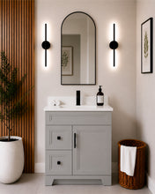 Pearl 30" light grey bathroom vanity with two drawers, black hardware and white quartz countertop, styled in a modern bathroom with wood slat accent wall
