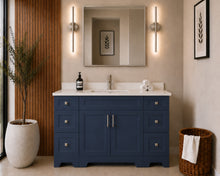 Pearl 54" navy blue bathroom vanity with six drawers, brushed nickel hardware and white quartz countertop, styled in a modern bathroom with wood slat accent wall